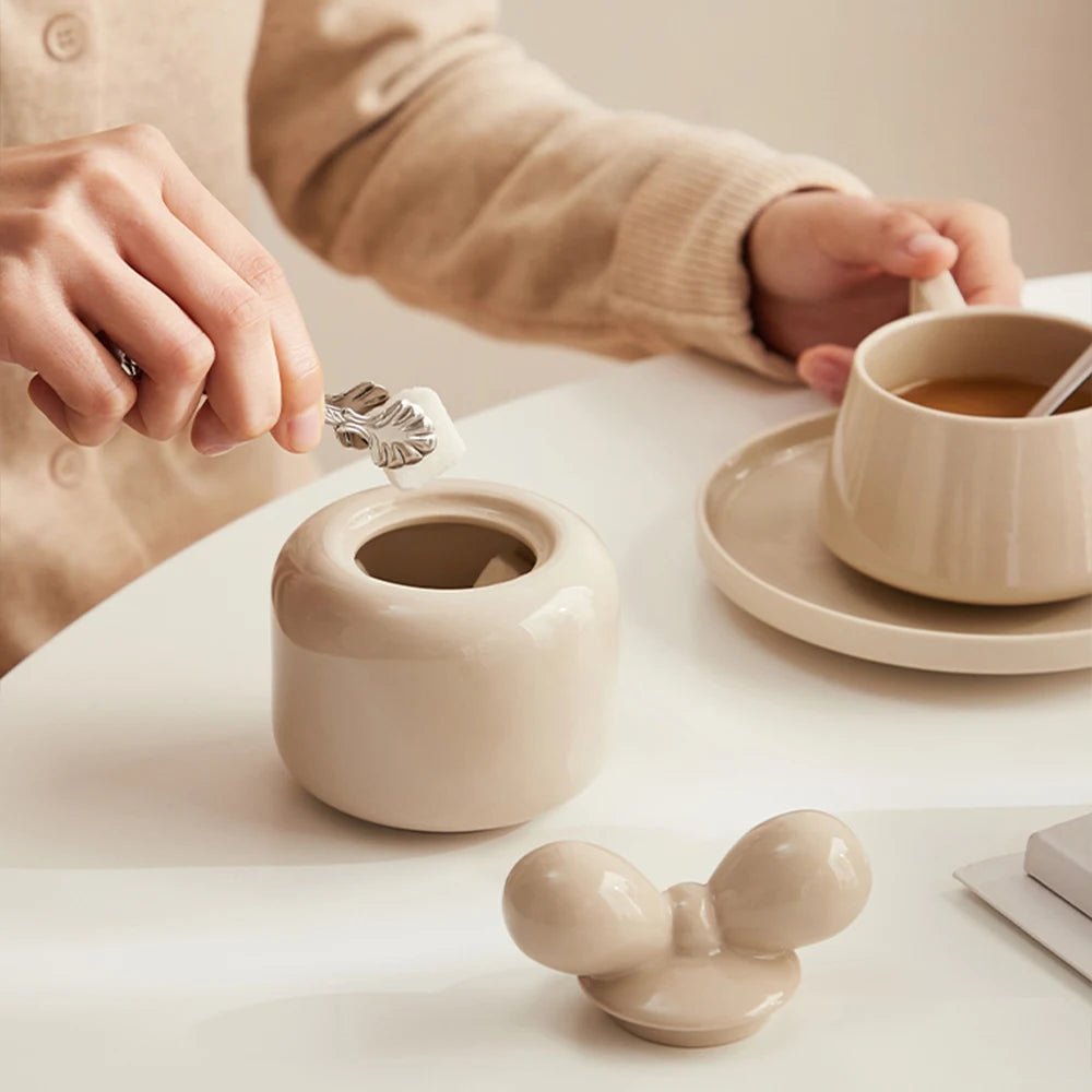 Une tasse de café et une théière en céramique blanche posées sur une table.