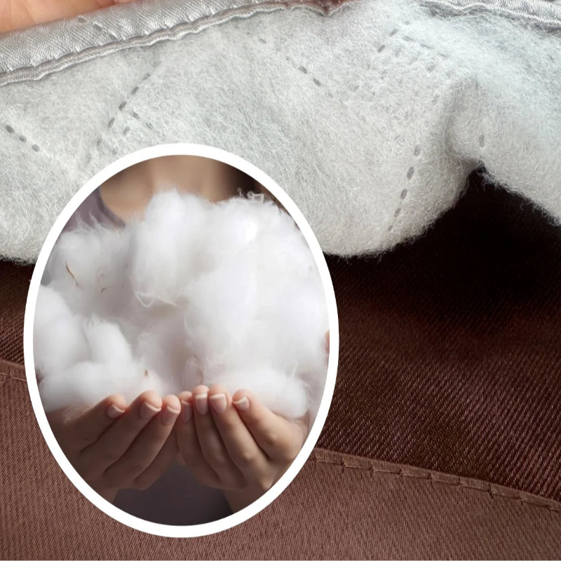 Image en gros plan d'une couette avec une section mise en avant, montrant une texture douce et moelleuse. Les mains tiennent délicatement du rembourrage, illustrant le confort et la légèreté du produit, idéal pour améliorer le sommeil et le bien-être durant les nuits.