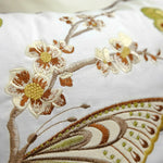 Un gros plan de motifs floraux brodés avec des couleurs chaudes sur un tissu blanc.