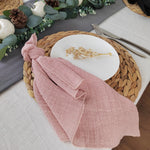 Une belle composition florale avec une serviette de table rose pâle sur un plateau en osier, accompagnée d'une décoration de Noël naturelle.