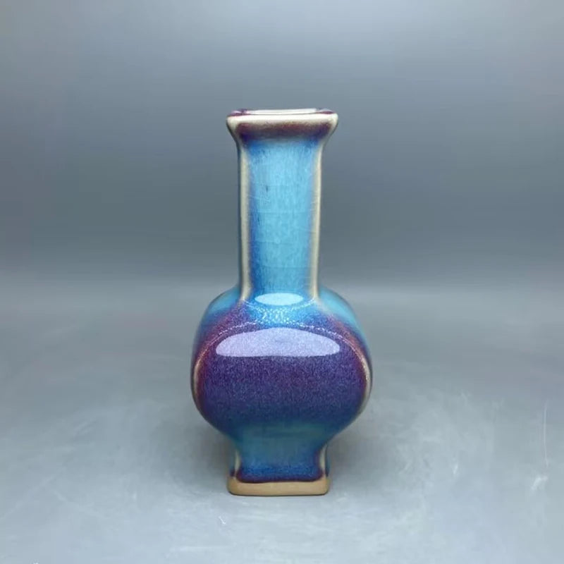 Vase en céramique de couleur bleue et violette, avec une forme arrondie et un long col étroit.
