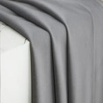 Zoom sur un tissu en velours gris posé sur un rebord en marbre blanc, mettant en valeur la texture douce et mate du rideau.