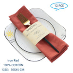 Des serviettes de table en coton rouges, pliées avec une fourchure dorée, posées sur des assiettes blanches avec le logo du jour bonjour au fond.