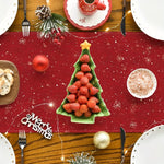 Une décoration de table de Noël avec un arbre de Noël en fraises, des boules de Noël rouges et dorées, et des éléments décoratifs sur un fond rouge pailleté.