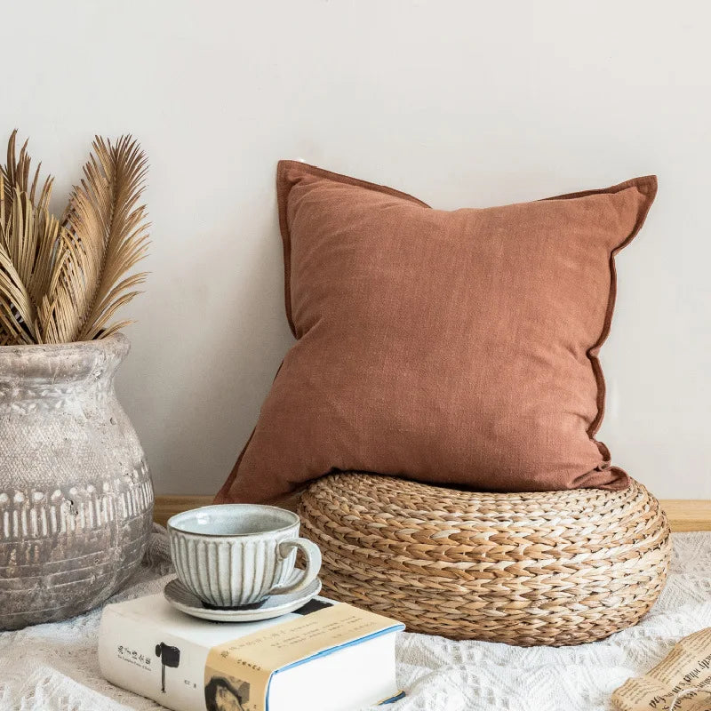 Tranquille coin cocooning avec coussin marron, tasse en céramique et plantes tropicales dans un pot en verre.