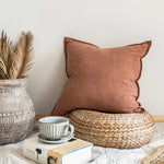 Tranquille coin cocooning avec coussin marron, tasse en céramique et plantes tropicales dans un pot en verre.