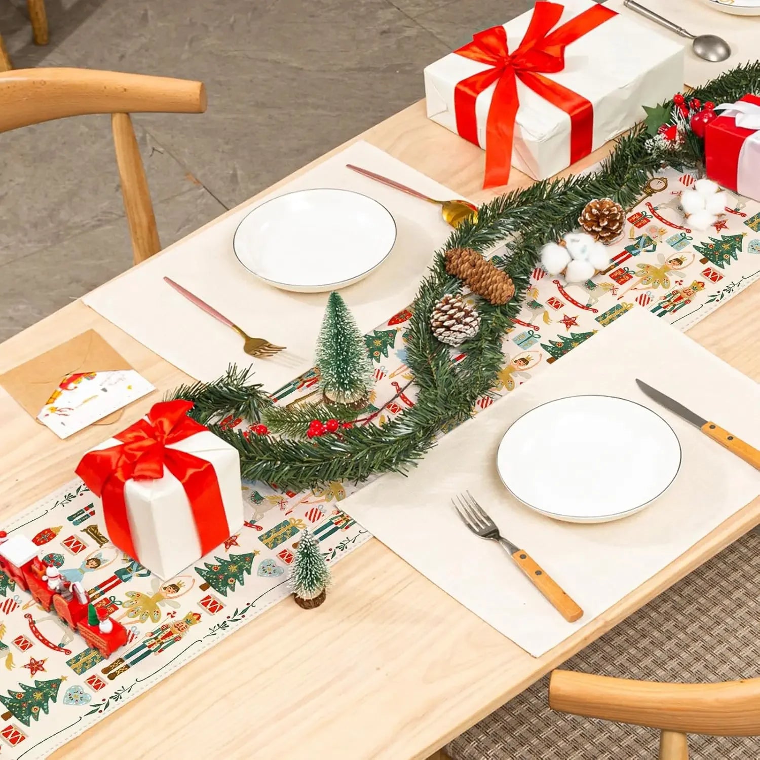 Une décoration de table de Noël festive avec des boîtes-cadeaux rouges, une couronne de Noël et des accessoires de fête sur une surface en bois.