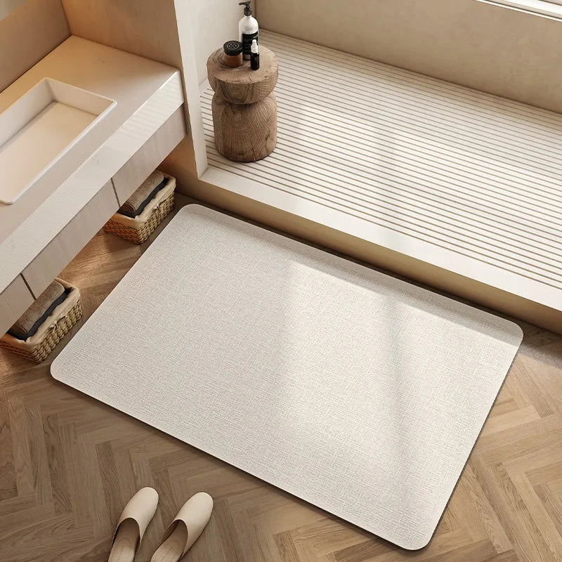 Tapis de bain de couleur beige, posé sur un parquet en bois, entouré d'éléments de décoration.