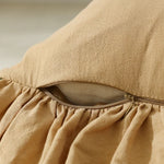 Une taie d'oreiller en lin de couleur beige, avec un motif de plis élégants et une fermeture éclair sur le côté.
