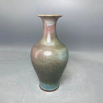 Le vase en céramique aux tons de verts, de bleus et de beiges avec une forme élégante.