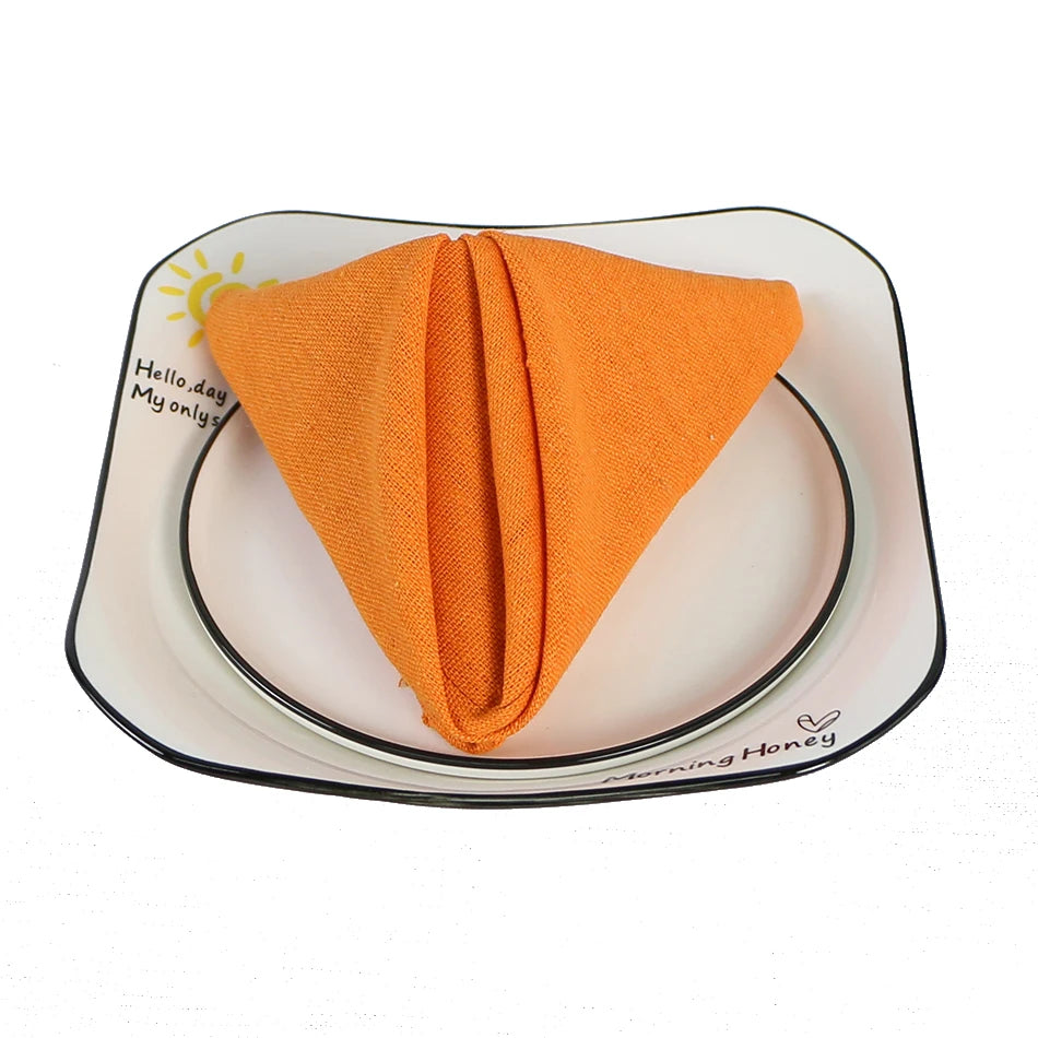 Une serviette de table orange vif posée sur une assiette plate blanche avec des bordures noires.