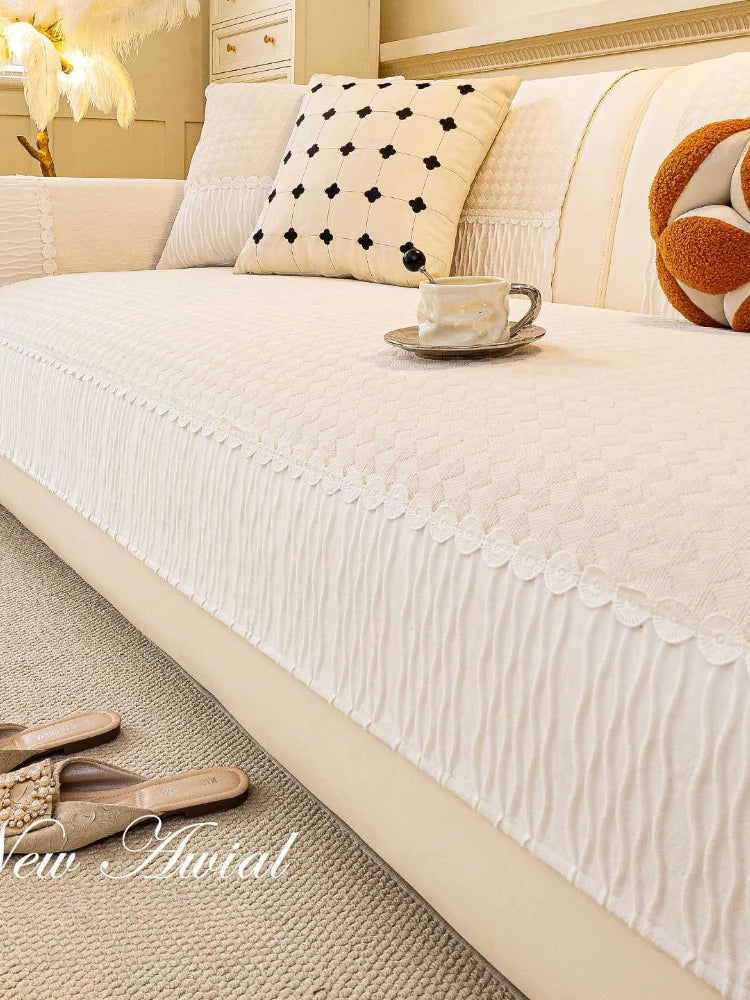 Un lit moelleux avec un joli plaid blanc et des coussins ornés de motifs graphiques, accompagnés d'une tasse de café sur la table basse, créent une atmosphère chaleureuse et confortable.