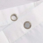 Gros plan sur les œillets métalliques du rideau, permettant une fixation aisée sur la tringle.