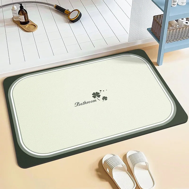 Un tapis de bain blanc et vert avec l'inscription "Bathroom" et des motifs de trèfle, posé sur un sol en bois clair, avec des accessoires de salle de bain à côté.