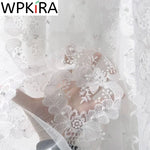 Rideau en tulle blanc perle suspendu à une fenêtre française