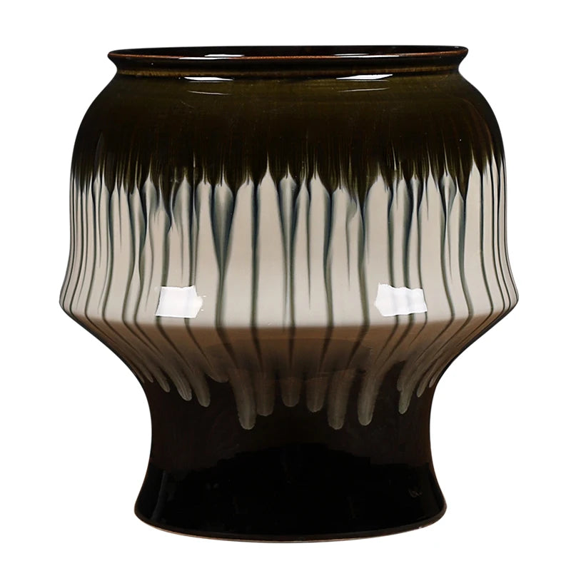 Un vase à motifs ondulés aux tons verts et noirs, conçu avec un design artistique et élégant.