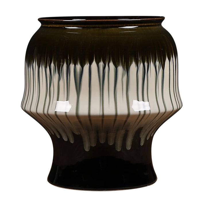 Un vase à motifs ondulés aux tons verts et noirs, conçu avec un design artistique et élégant.