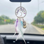 Un attrape-rêves suspendu dans la voiture, avec des plumes colorées et des pierres violettes formant un motif arbre de vie captivant.