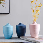Des vases colorés en céramique posés sur une table, avec des fleurs jaunes dans l'un d'eux, créant une belle décoration d'intérieur.