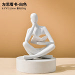 statue décorative résine figure humaine assise livre ouvert beige clair doré textures abstraites moderne