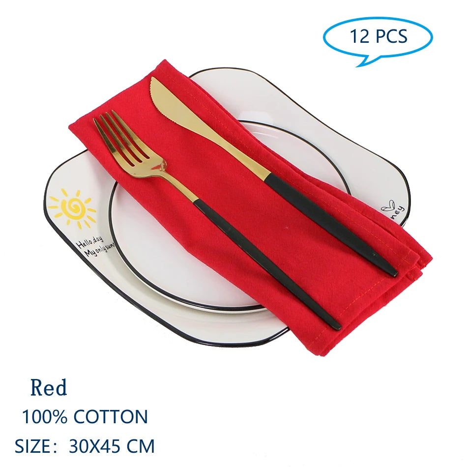 Serviettes en coton rouge pour la table, avec fourchette et couteau dorés, sur des assiettes blanches.