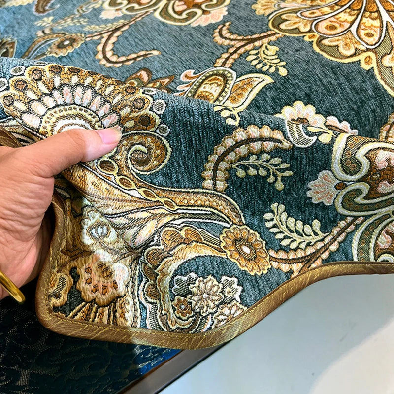 Cette image montre un motif textile décoratif fait de broderie et de motifs ornementaux dans des tons de bleu et d'or, créant un riche et élégant design.