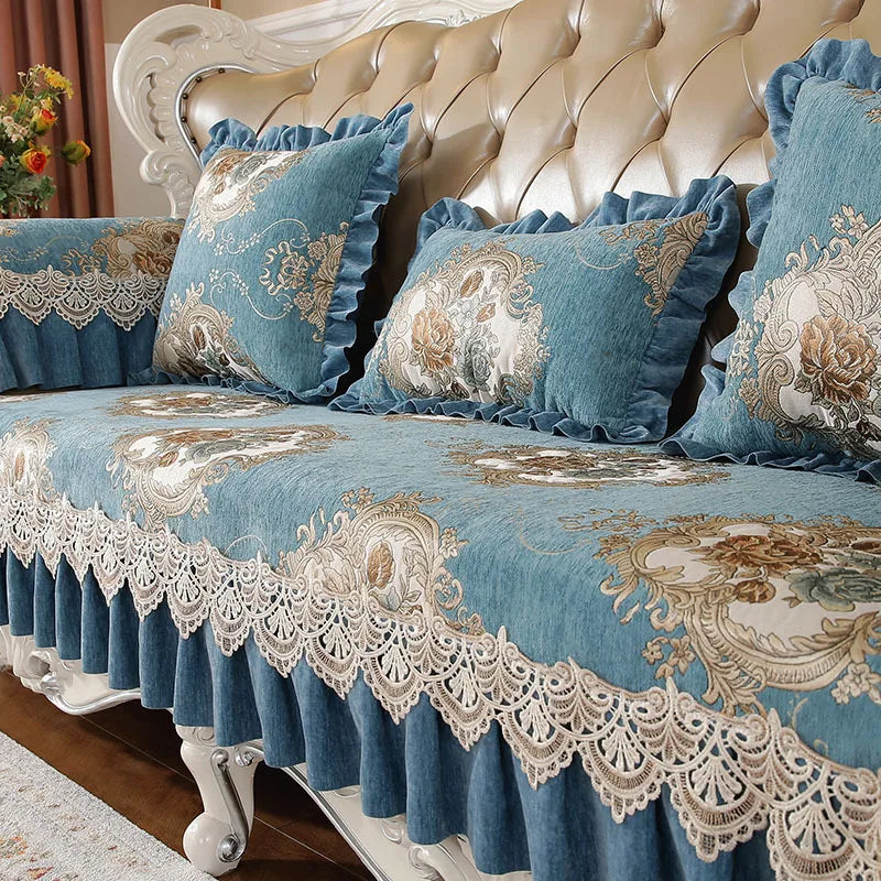 Ensemble de canapé luxueux en velours bleu avec motifs floraux dorés, garni de coussins et de dentelle, créant une ambiance élégante et sophistiquée dans le salon.