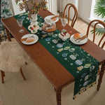 Une table en bois décorée de motifs de Noël avec des plats et des verres sur une nappe verte.