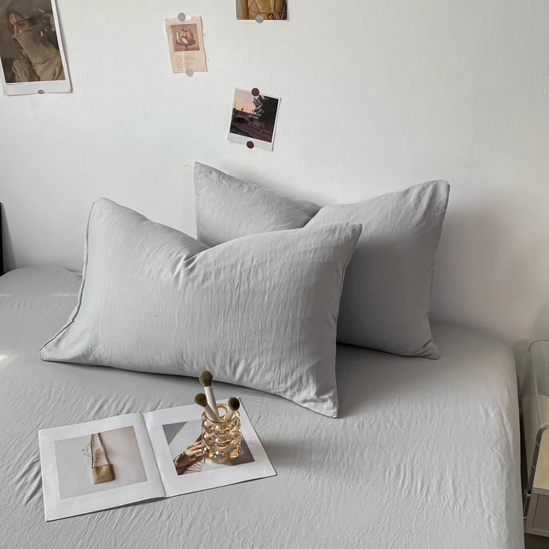 L'image montre un intérieur cozy avec des oreillers gris sur un canapé, des cadres photos sur le mur et des éléments de décoration, créant une atmosphère apaisante et intime.