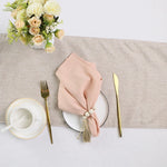 Une table élégante avec un bouquet de fleurs blanches et roses, une assiette et des couverts dorés, et une serviette de table rose nouée avec une décoration.