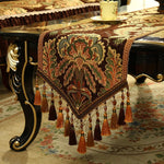 Un magnifique chemin de table en jacquard orné de motifs floraux richement colorés et de glands décoratifs, conférant une élégance traditionnelle à la décoration d'intérieur.