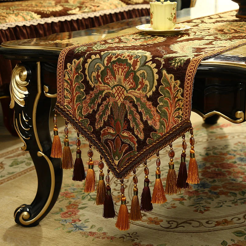 Un magnifique chemin de table en jacquard orné de motifs floraux richement colorés et de glands décoratifs, conférant une élégance traditionnelle à la décoration d'intérieur.