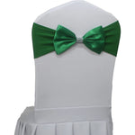 Élégant noeud papillon vert sur une housse de chaise blanche, accessoire décoratif raffiné pour une soirée élégante.