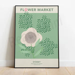 Affiche stylisée représentant un marché aux fleurs à Sydney, avec une fleur blanche au centre entourée de touches de vert représentant la végétation.