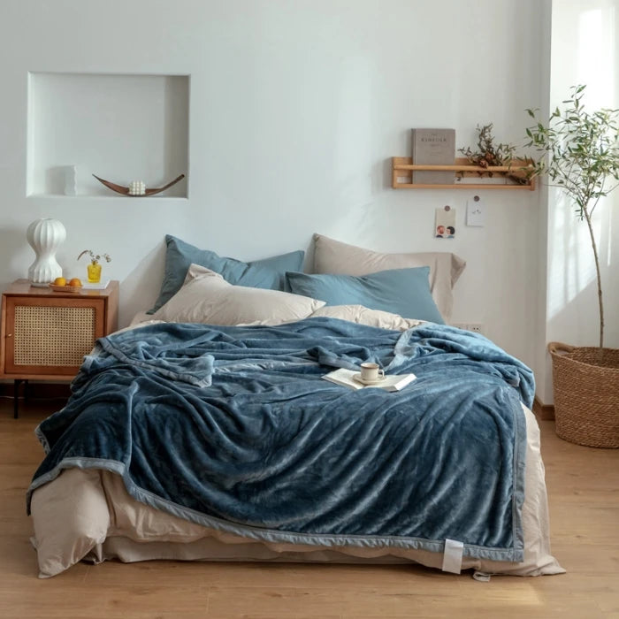 Une chambre à coucher élégante et chaleureuse, avec un lit confortable recouvert de draps bleus et beiges, une étagère murale en bois, une plante verte et un aménagement intérieur harmonieux.