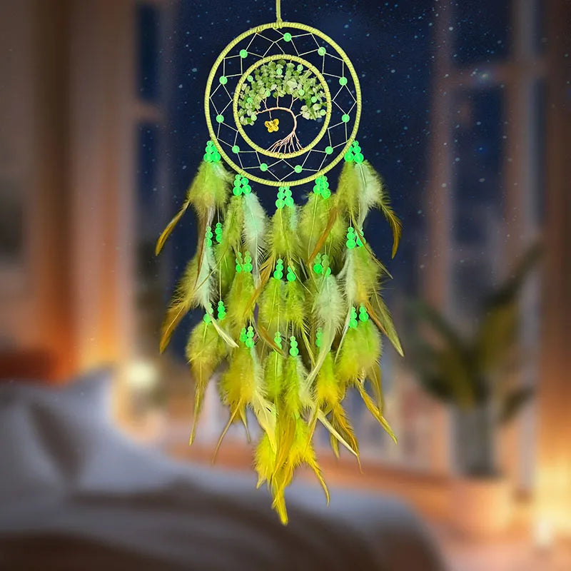 Un capteur de rêves fait main et décoratif, constitué d'un anneau noir avec un arbre de vie verdoyant représenté au centre, entouré de plumes jaunes et vertes.
