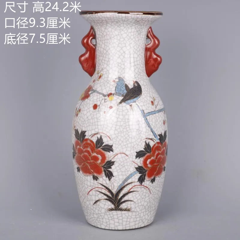 Ce vase en céramique d'aspect craquelé est orné de fleurs rouges aux motifs floraux détaillés et d'un oiseau gris, créant une pièce décorative élégante.
