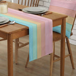 Une table en bois avec une belle nappe multicolore, disposée sur un sol en parquet, avec des chaises autour pour un repas convivial.