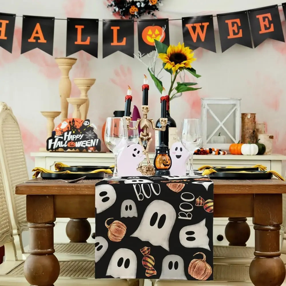 Une table de fête décorée pour Halloween avec des fantômes, des citrouilles et des bougies sur un fond de bannière festive.