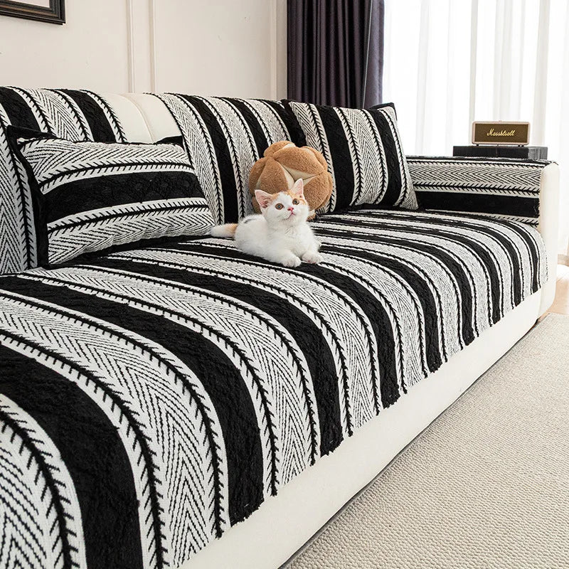 Un chat blanc reposant sur le lit aux motifs géométriques noirs et blancs.