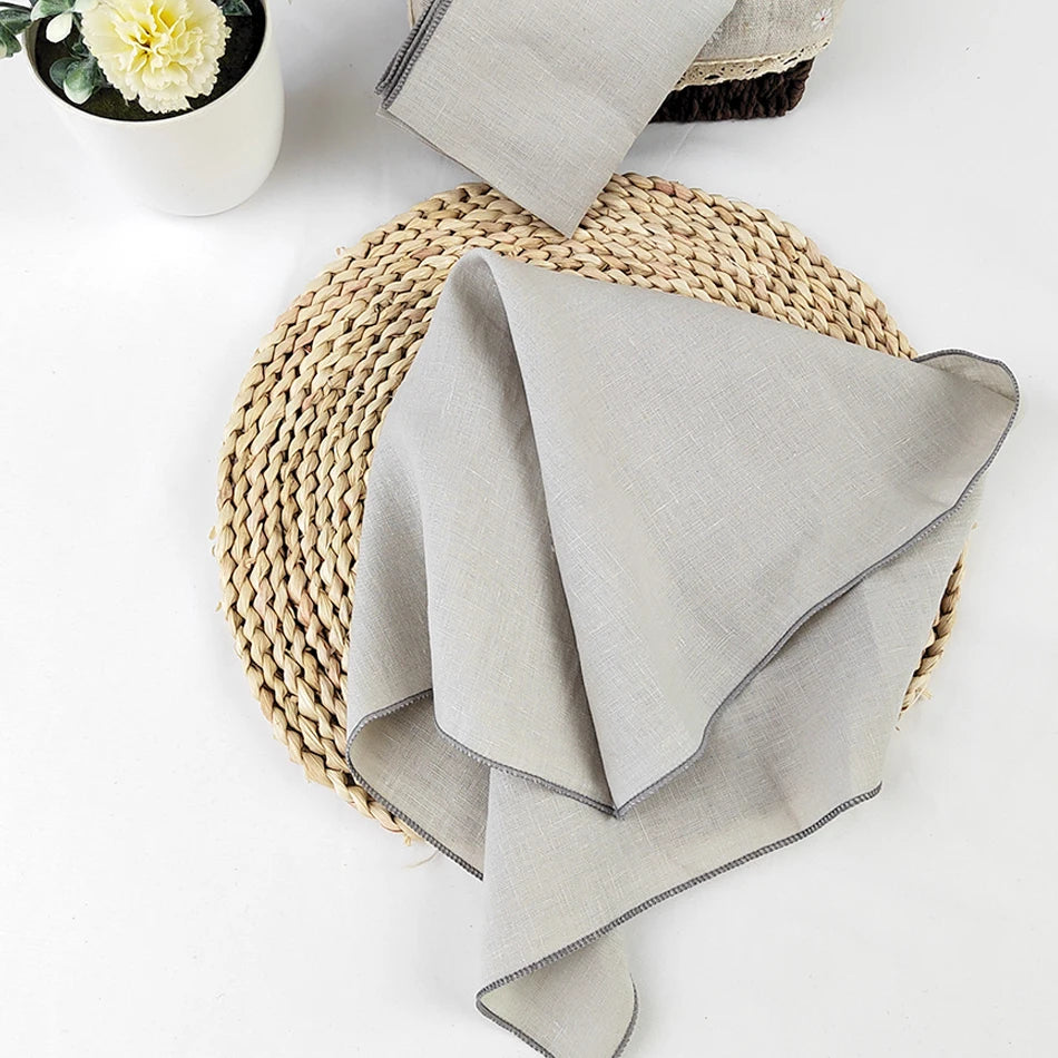Une nappe de table en fibre de papier tressée, accompagnée d'un pot de fleurs et d'un tissu gris.