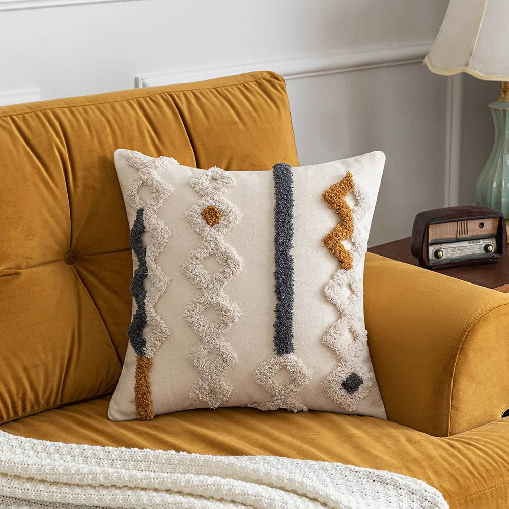 Le coussin beige et jaune orné de motifs texturés orne agréablement le canapé moelleux, créant une ambiance chaleureuse et accueillante dans la pièce.
