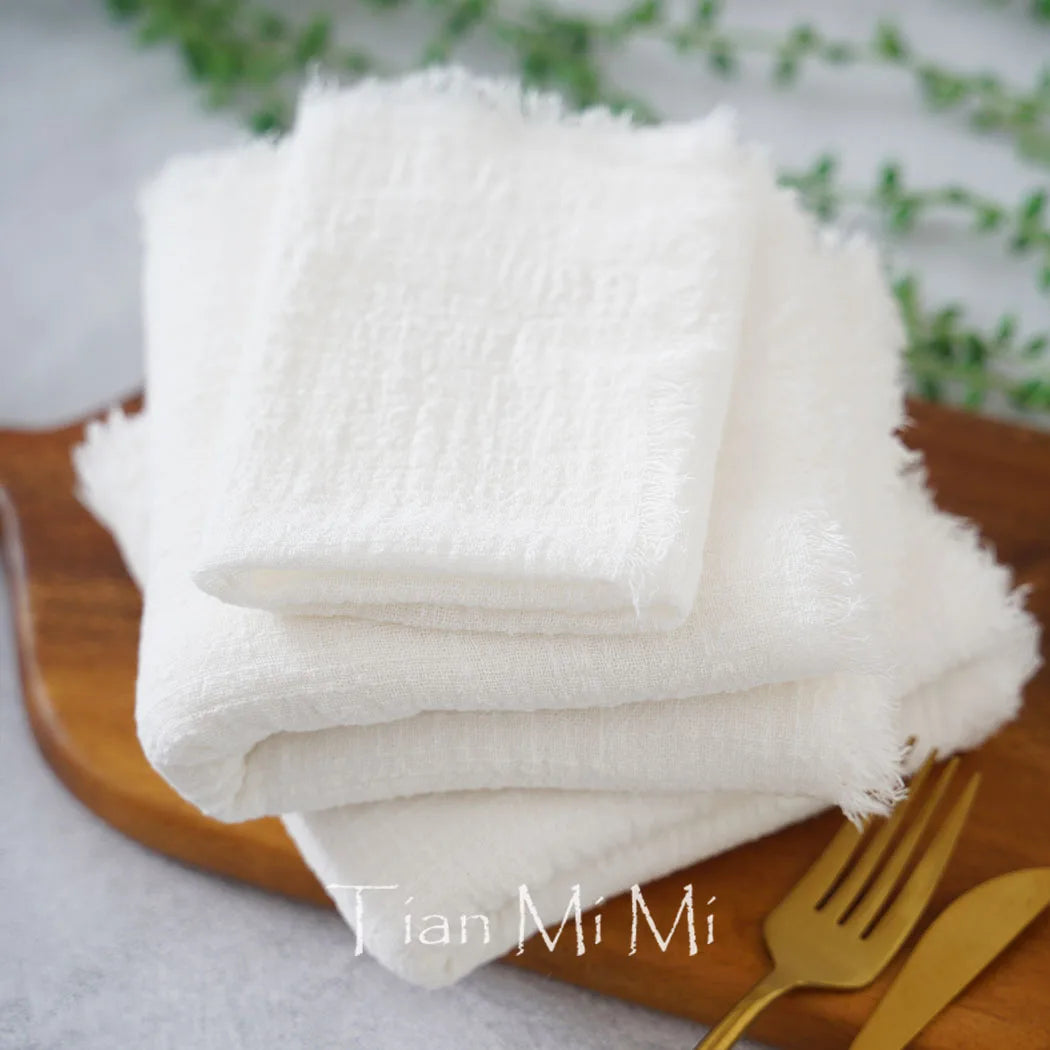 Le gros plan montre de nombreuses serviettes blanches moelleuses disposées sur un plateau en bois, accompagnées de couverts en métal doré, créant une atmosphère propre et soignée.