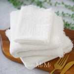 Le gros plan montre de nombreuses serviettes blanches moelleuses disposées sur un plateau en bois, accompagnées de couverts en métal doré, créant une atmosphère propre et soignée.