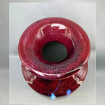Vase en verre de forme ronde et teinte rouge foncé, avec une surface texturée et brillante, et des éléments décoratifs bleu pâle incrustés dans le verre.
