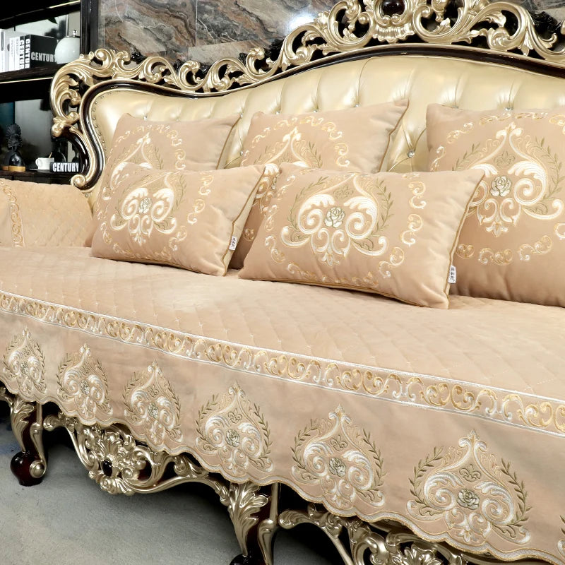 Un canapé ancien de style baroque avec un cadre orné de motifs floraux et des coussins en velours beige pâle.