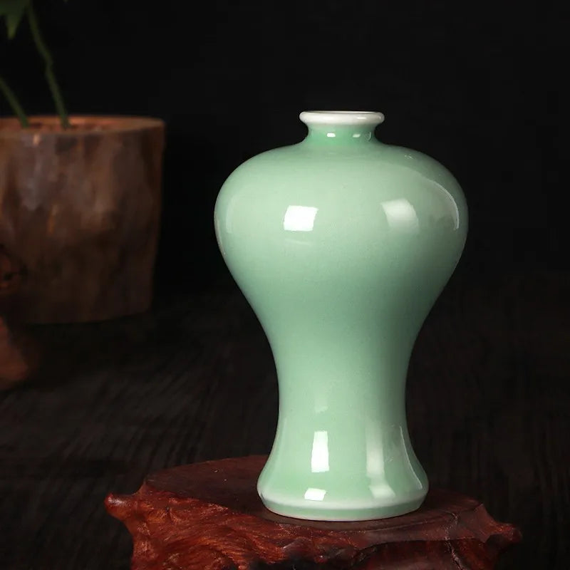 Vase en céramique de couleur vert pâle sur un support en bois foncé.