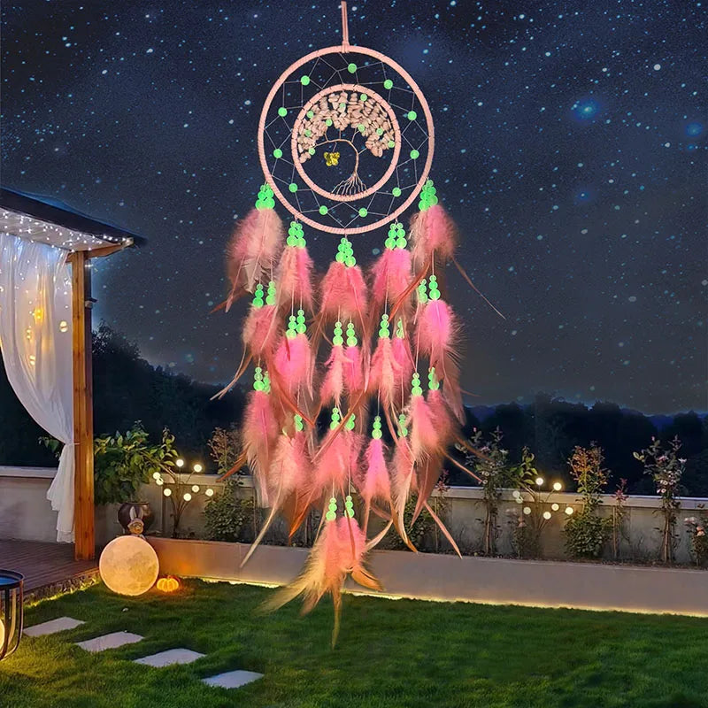 Un capteur de rêves coloré et lumineux suspendu dans un jardin nocturne, avec de jolies plumes roses et des éléments verts luminescents.