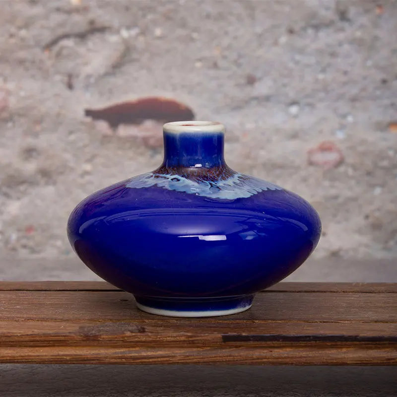 Un magnifique vase en céramique bleu foncé avec des motifs texturés, posé sur une surface en bois rustique.