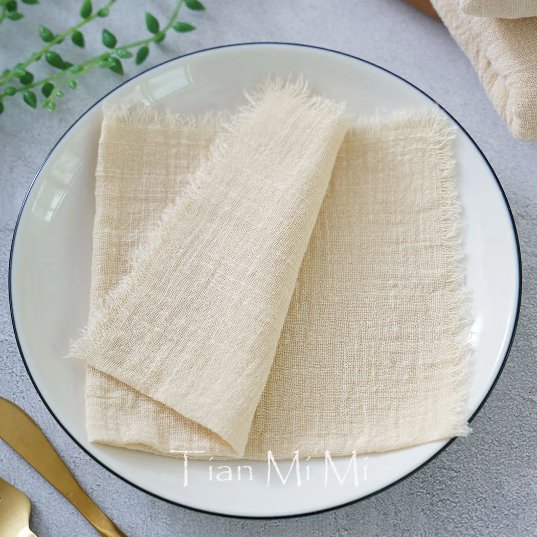 Serviette blanche et lâche délicatement posée sur une assiette blanche avec des feuilles vertes en arrière-plan.
